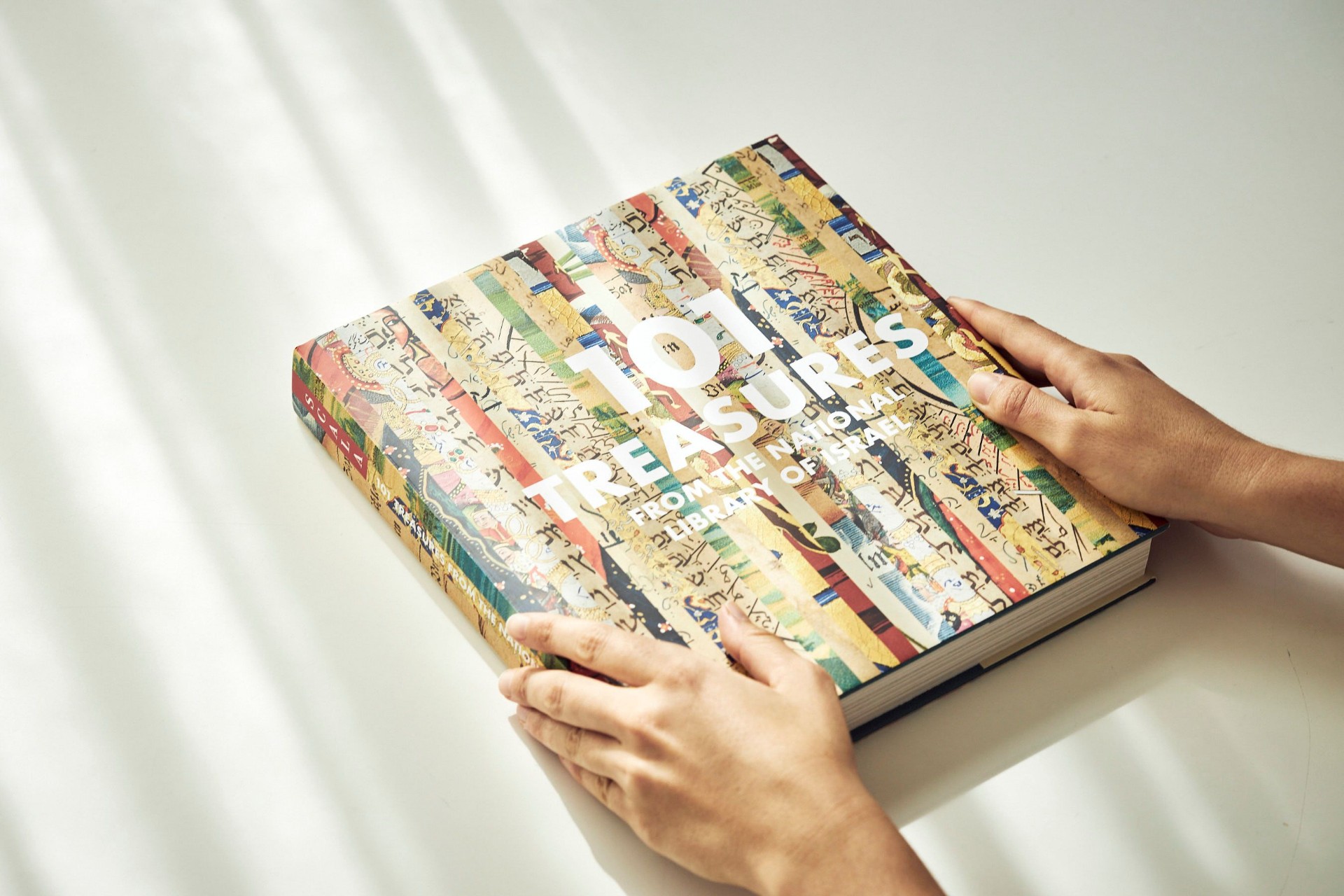 101 Treasures from the National Library of Israel — hardcover book held in two hands